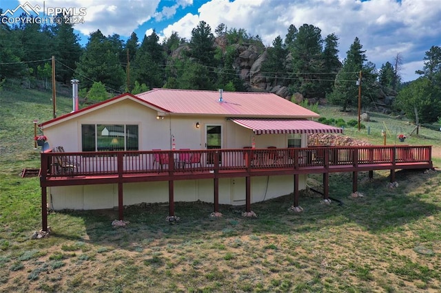 rear view of house featuring a wooden deck and a yard