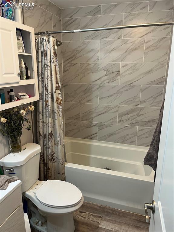 full bathroom featuring hardwood / wood-style floors, vanity, toilet, and shower / bathtub combination with curtain