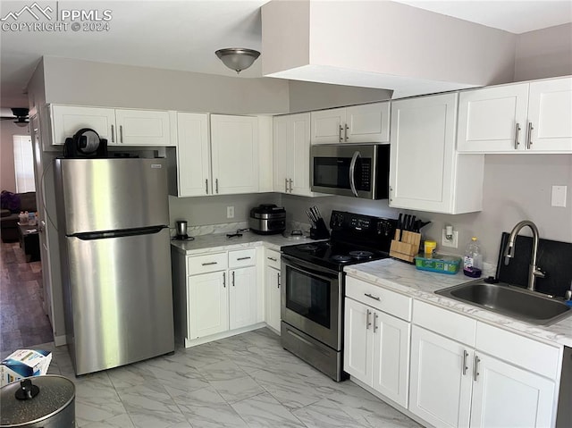 kitchen featuring light stone counters, white cabinetry, sink, and appliances with stainless steel finishes