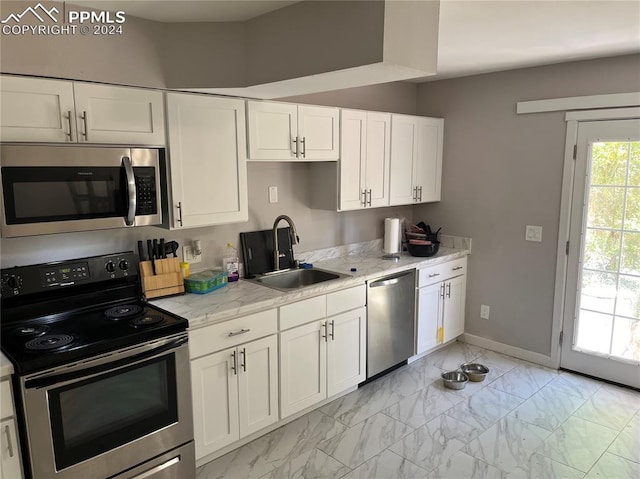 kitchen featuring white cabinets, light stone counters, sink, and appliances with stainless steel finishes