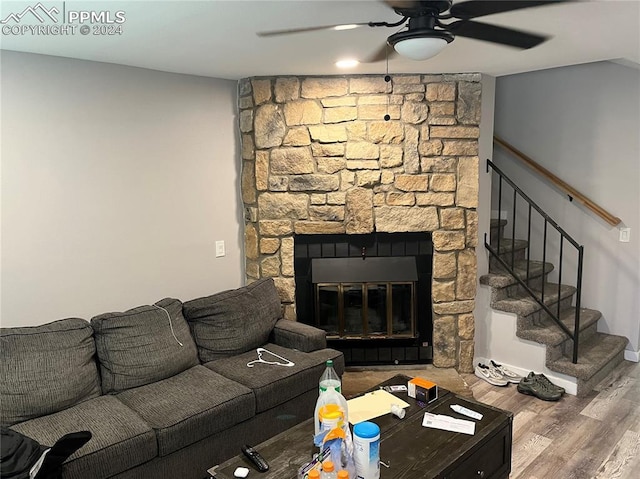 living room featuring a stone fireplace, ceiling fan, and wood-type flooring