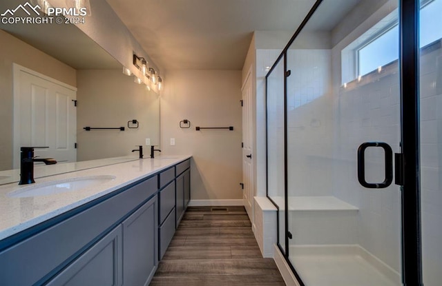 bathroom featuring a shower with door, dual bowl vanity, and hardwood / wood-style floors