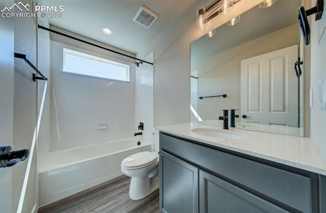 full bathroom with hardwood / wood-style floors, vanity with extensive cabinet space, toilet, and tiled shower / bath