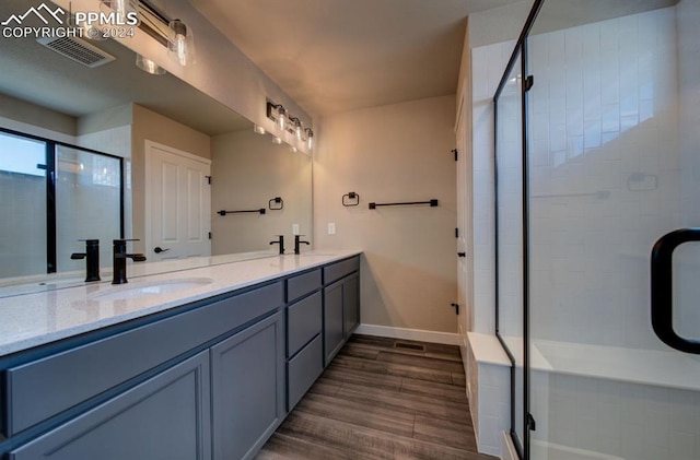 bathroom with a shower with door, hardwood / wood-style flooring, and dual vanity