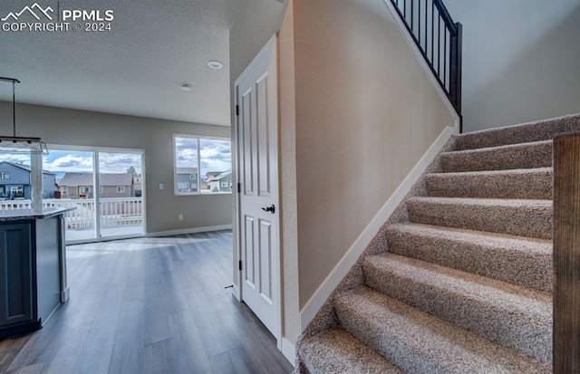 stairs with a textured ceiling and dark hardwood / wood-style flooring