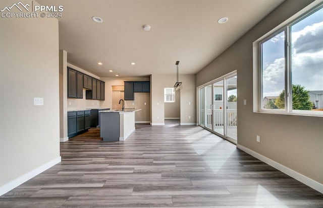 kitchen with hanging light fixtures, a kitchen island with sink, hardwood / wood-style floors, and a wealth of natural light