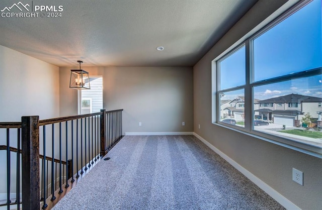 carpeted empty room featuring a wealth of natural light and a textured ceiling