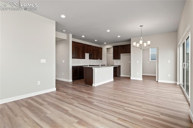 kitchen featuring pendant lighting, a kitchen island with sink, sink, light hardwood / wood-style flooring, and a chandelier