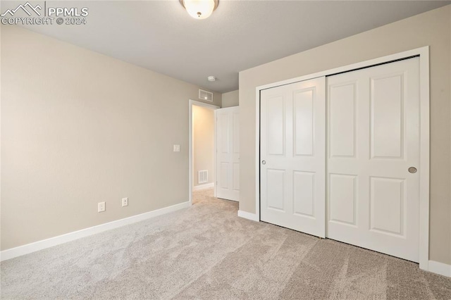 unfurnished bedroom featuring a closet and light colored carpet