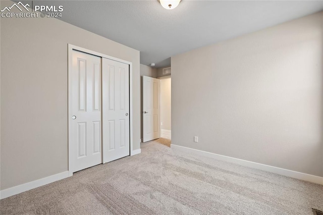 unfurnished bedroom featuring light carpet and a closet