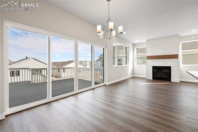 unfurnished living room featuring a tile fireplace, a chandelier, and dark hardwood / wood-style floors