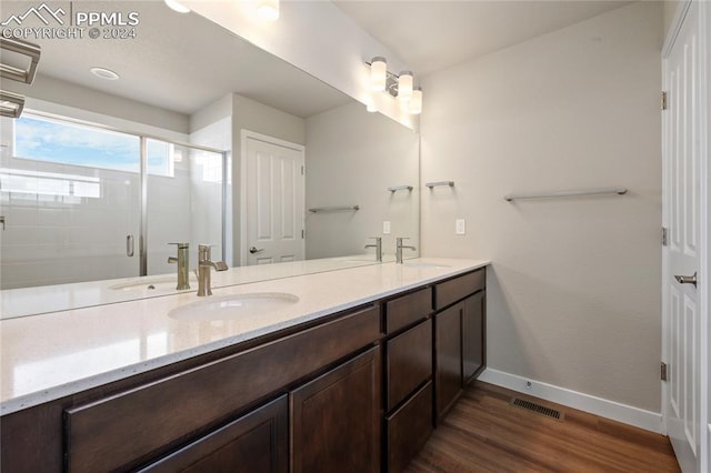 bathroom with hardwood / wood-style floors, vanity, and a shower with shower door