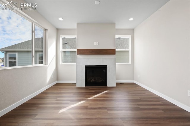 unfurnished living room featuring a tile fireplace and dark wood-type flooring