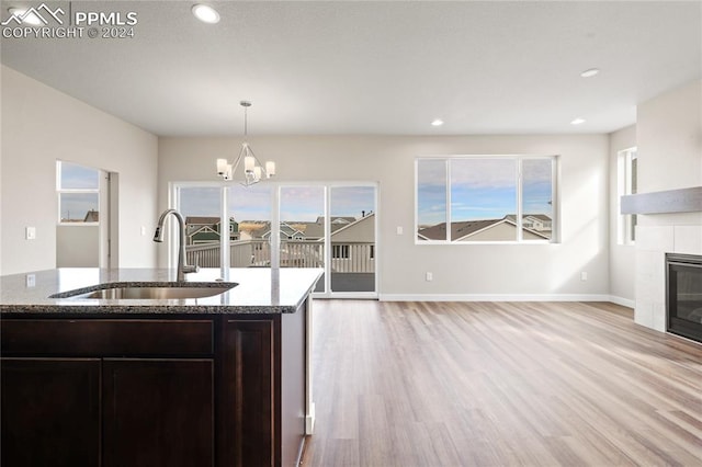 kitchen with a tiled fireplace, sink, dark brown cabinets, and stone countertops