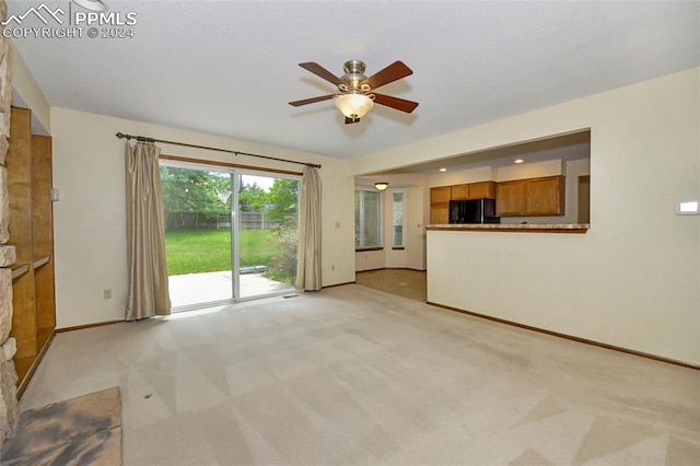 unfurnished living room featuring ceiling fan and light colored carpet