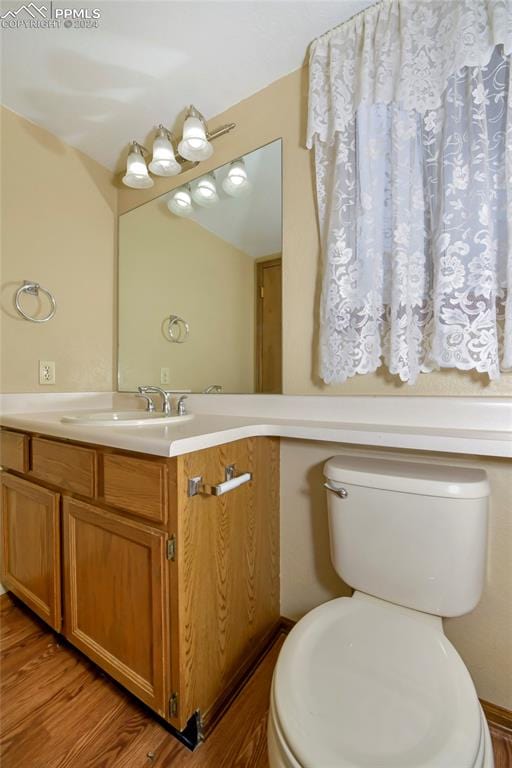 bathroom with hardwood / wood-style floors, toilet, and vanity