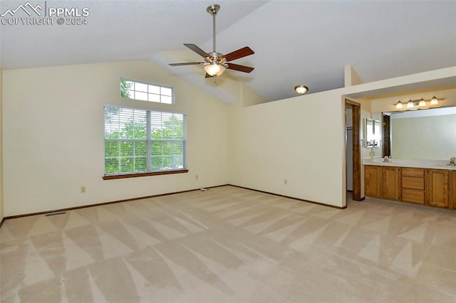 unfurnished bedroom with ceiling fan, light carpet, sink, ensuite bath, and lofted ceiling