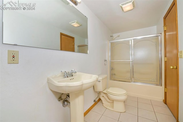 bathroom featuring shower / bath combination with glass door, toilet, and tile floors