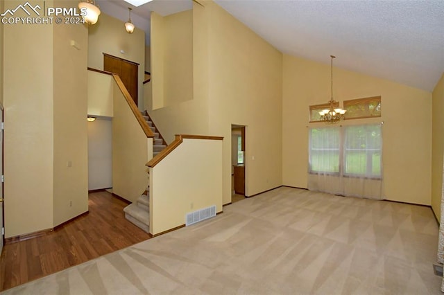 empty room featuring a chandelier, a textured ceiling, high vaulted ceiling, and carpet