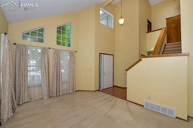 interior space with high vaulted ceiling and carpet flooring