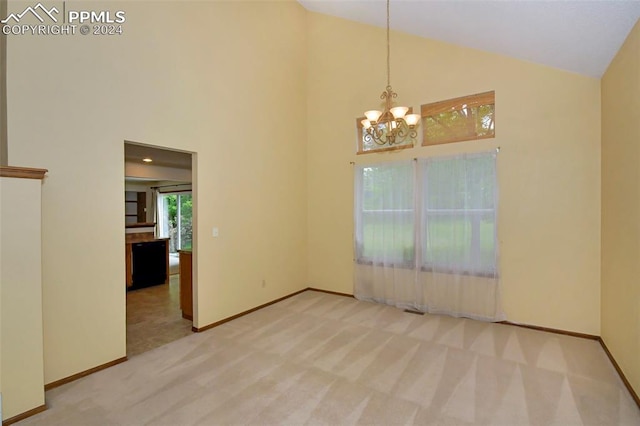 empty room with high vaulted ceiling, a notable chandelier, and carpet