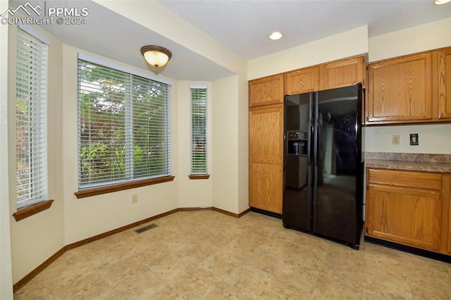 kitchen featuring black fridge with ice dispenser and light tile floors