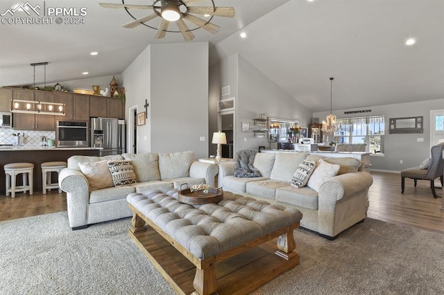 living room featuring ceiling fan with notable chandelier, high vaulted ceiling, and dark wood-type flooring