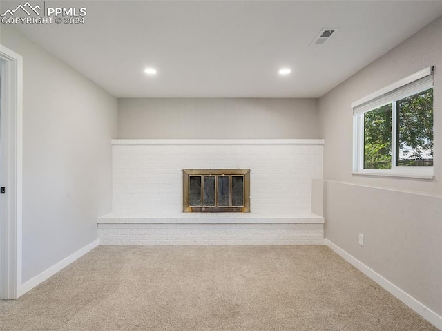 unfurnished living room featuring carpet flooring and a brick fireplace