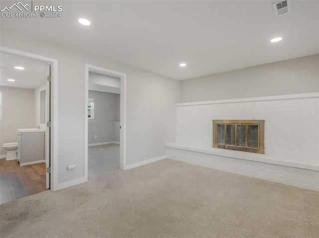 unfurnished living room with sink, carpet flooring, and a brick fireplace