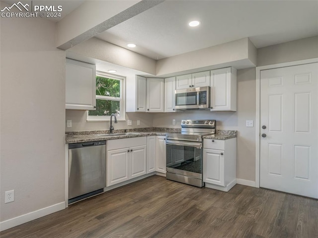 kitchen with dark hardwood / wood-style floors, stone counters, sink, white cabinets, and appliances with stainless steel finishes