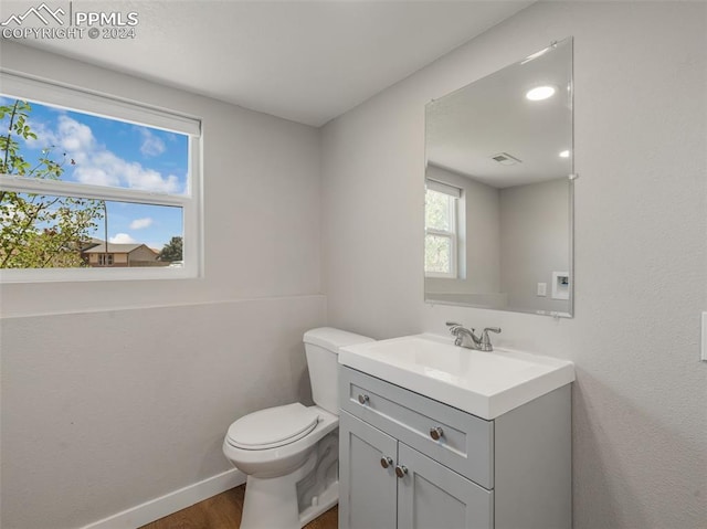 bathroom featuring hardwood / wood-style floors, vanity with extensive cabinet space, and toilet