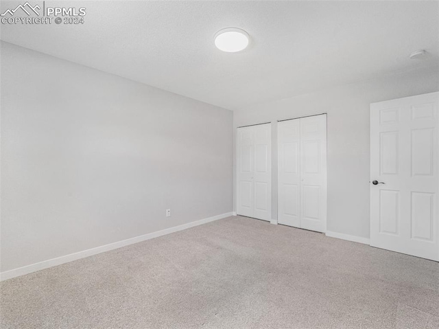 unfurnished bedroom featuring carpet floors and multiple closets