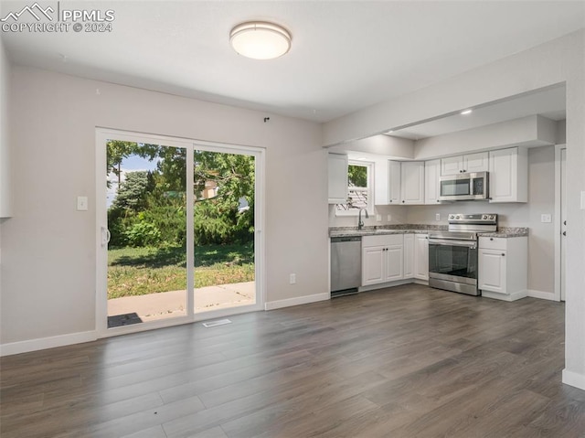 kitchen featuring white cabinets, appliances with stainless steel finishes, dark hardwood / wood-style flooring, and light stone counters