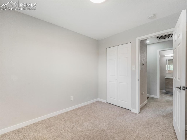 unfurnished bedroom with light colored carpet and a closet