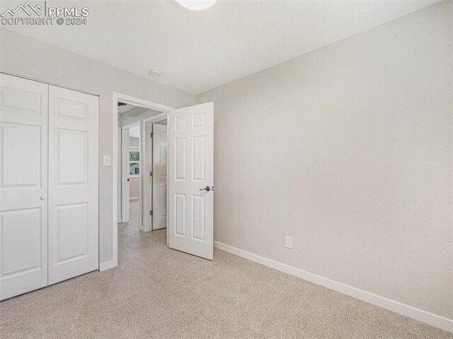 unfurnished bedroom featuring a closet and light colored carpet