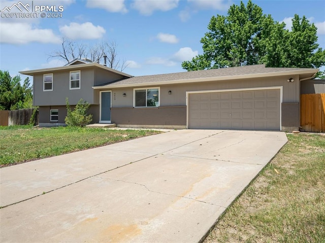 tri-level home featuring a garage and a front lawn