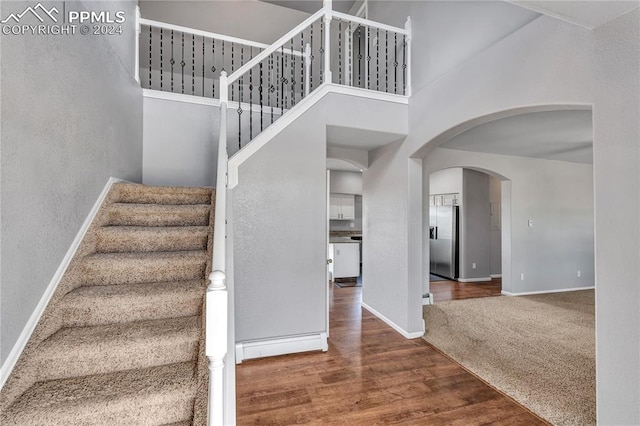 stairs with carpet and a high ceiling