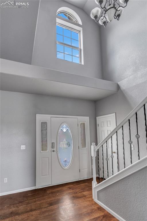 entryway featuring a high ceiling, dark hardwood / wood-style floors, and a notable chandelier