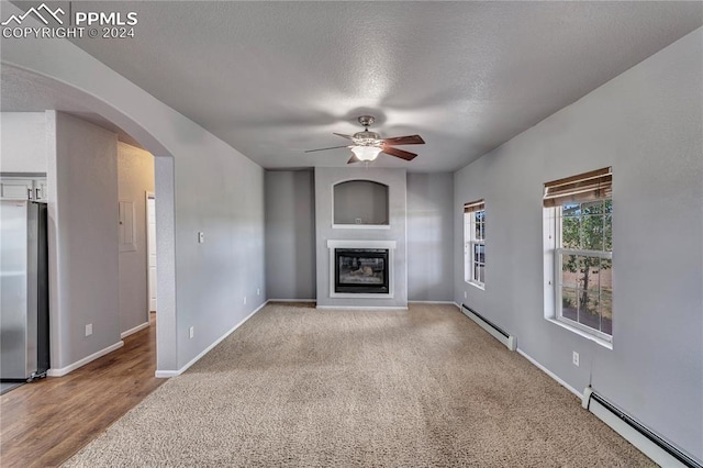 unfurnished living room with a textured ceiling, ceiling fan, light carpet, and a baseboard radiator