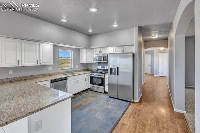 kitchen featuring white cabinets, sink, stainless steel appliances, and a textured ceiling