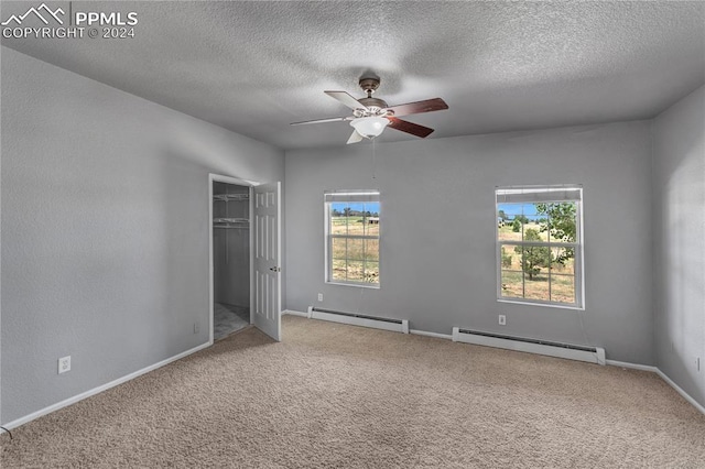 unfurnished bedroom with multiple windows, ceiling fan, and a baseboard heating unit