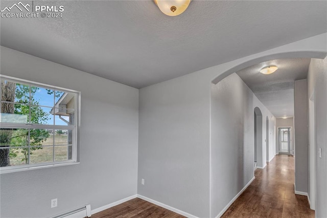 unfurnished room with dark wood-type flooring and a baseboard radiator