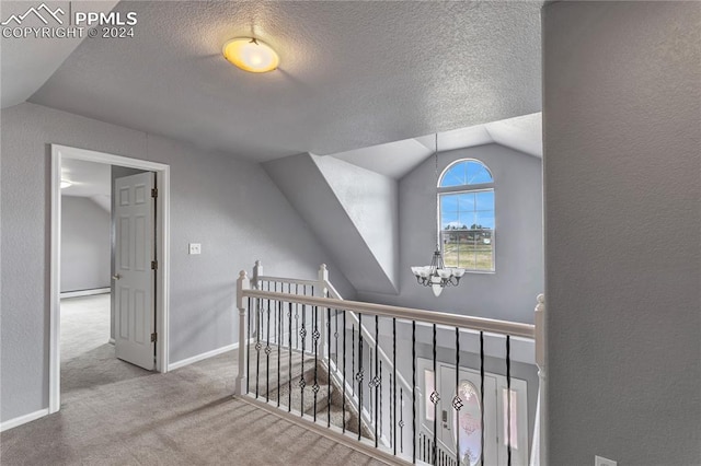 corridor featuring a baseboard heating unit, vaulted ceiling, carpet flooring, a textured ceiling, and a chandelier