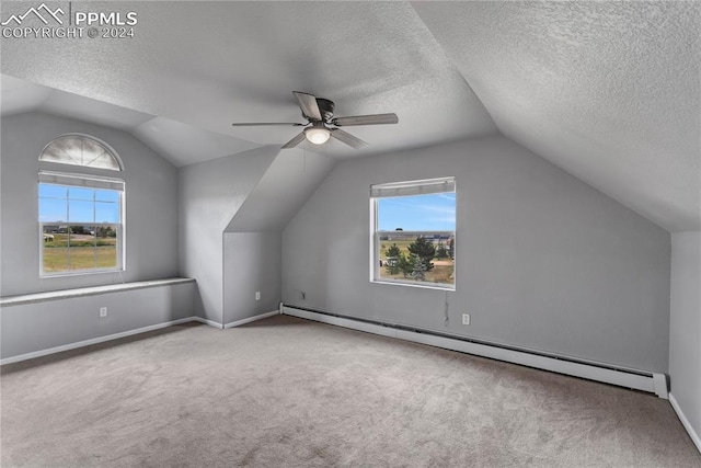 bonus room with lofted ceiling, ceiling fan, a textured ceiling, a wealth of natural light, and a baseboard radiator