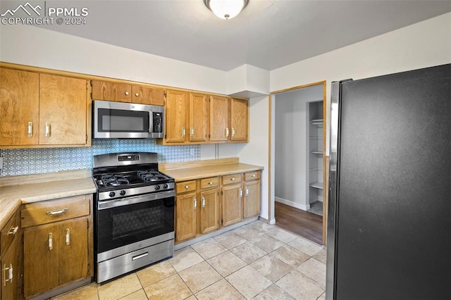 kitchen featuring light tile patterned flooring, decorative backsplash, and stainless steel appliances