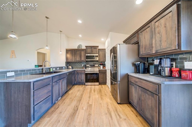 kitchen with lofted ceiling, sink, hanging light fixtures, tasteful backsplash, and stainless steel appliances