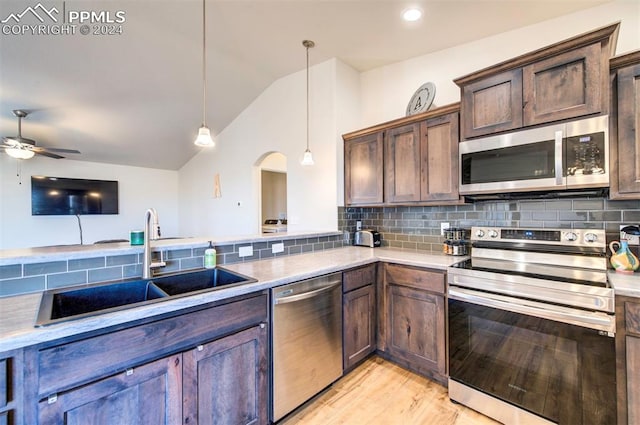 kitchen featuring backsplash, sink, hanging light fixtures, vaulted ceiling, and stainless steel appliances