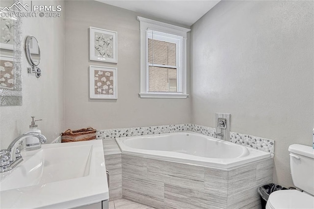 bathroom with tiled bath, vanity, and toilet