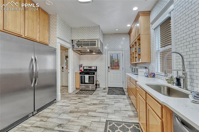 kitchen with light brown cabinetry, sink, wall chimney exhaust hood, and stainless steel appliances