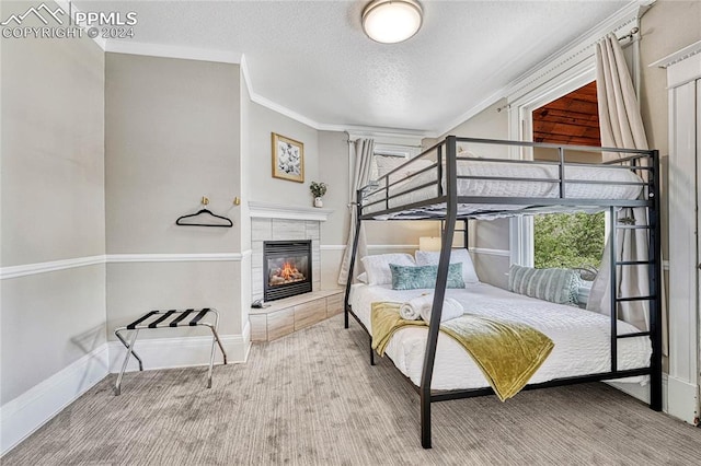 carpeted bedroom featuring a tile fireplace, crown molding, and a textured ceiling